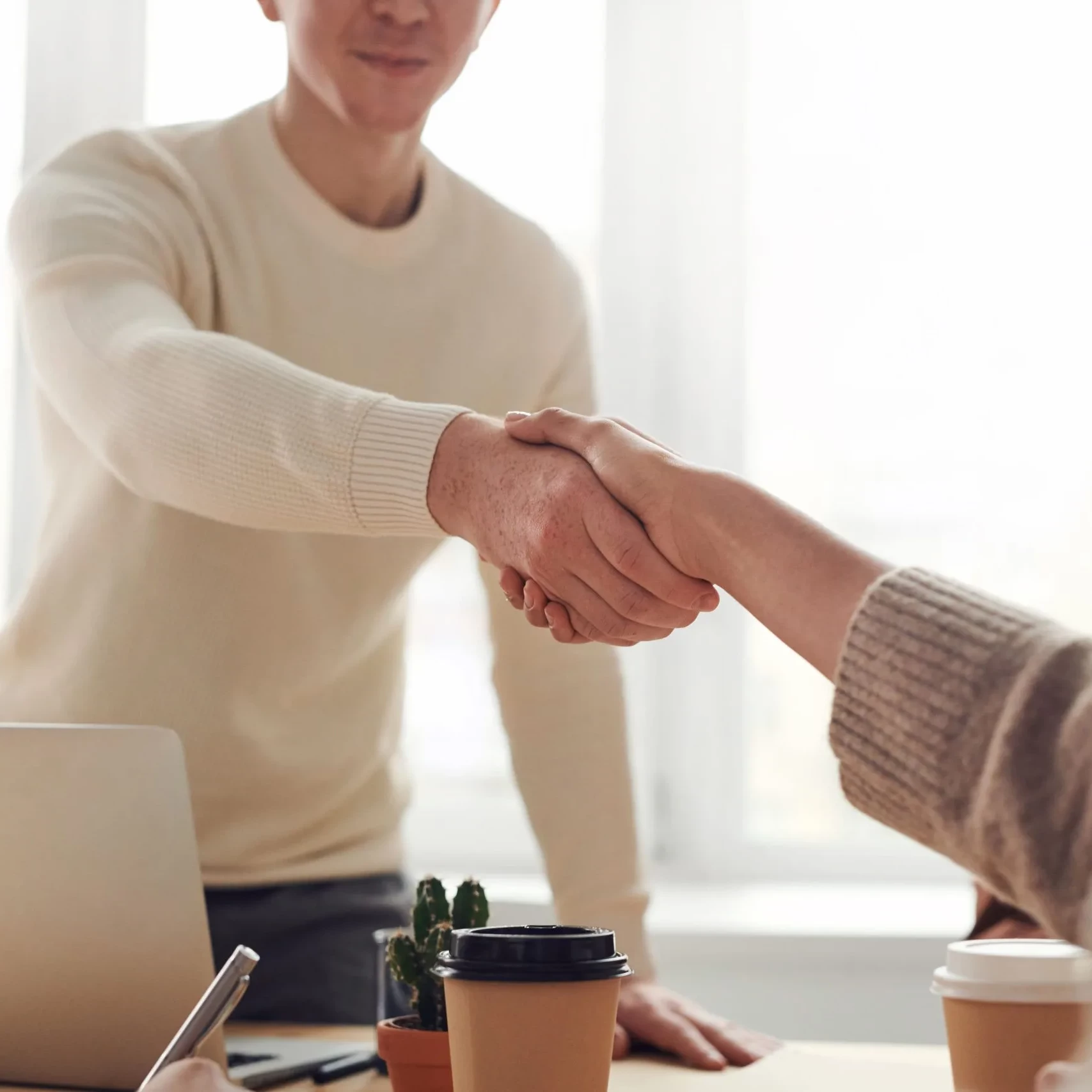Man en een vrouw die elkaar een hand geven aan een bureau. Op een nieuwe deal voor het genereren van nieuwe leads.